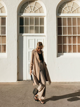 a lady wears a classic trench coat with beige wide leg pants